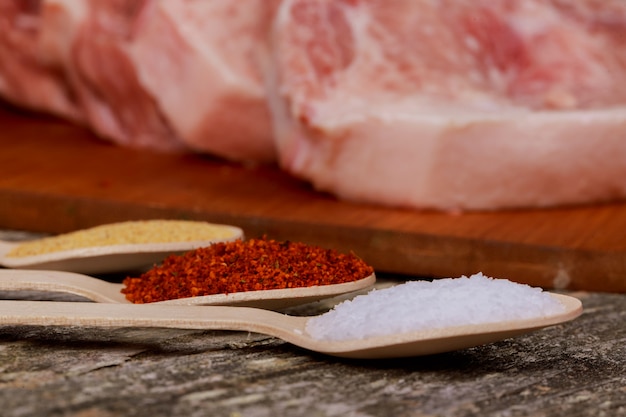 Pezzo di lonza di maiale cruda sul vecchio tagliere, carne di maiale in umido crudo e spezie