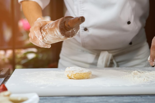 Pezzo di pasta e farina mani maschili tenere il mattarello chef prepara l'ingrediente chiave dell'impasto per la torta