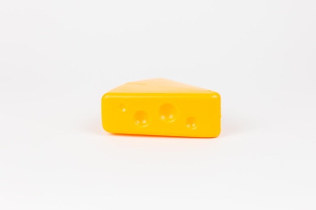 Pezzo di plastica giocattolo di formaggio masdam su sfondo bianco