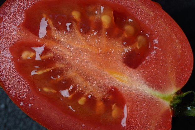 Pezzo di pomodoro fresco tagliato su sfondo scuro