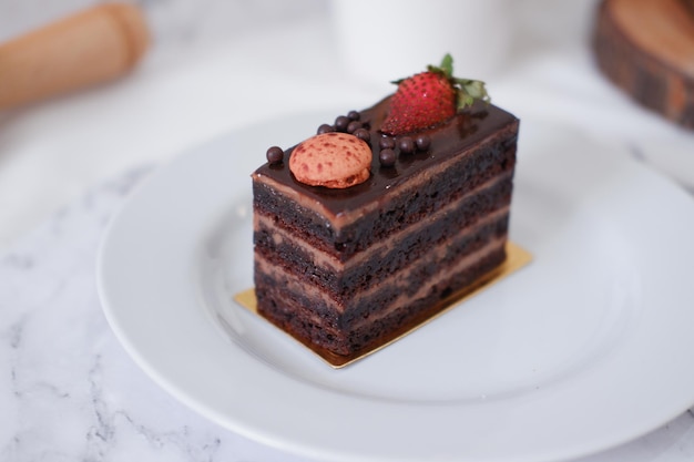 Pezzo di torta al cioccolato con fragole e amaretti su piatto bianco