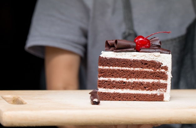 Pezzo di torta al cioccolato con glassa alla vaniglia e gelatina di ciliegie.