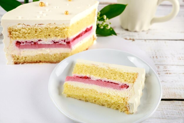 Pezzo di torta di compleanno con rose bianche su sfondo bianco.