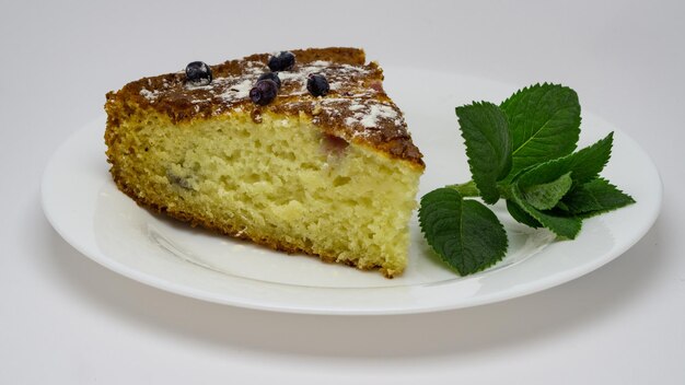 pezzo di torta di mirtilli, torta su un piatto bianco con menta verde