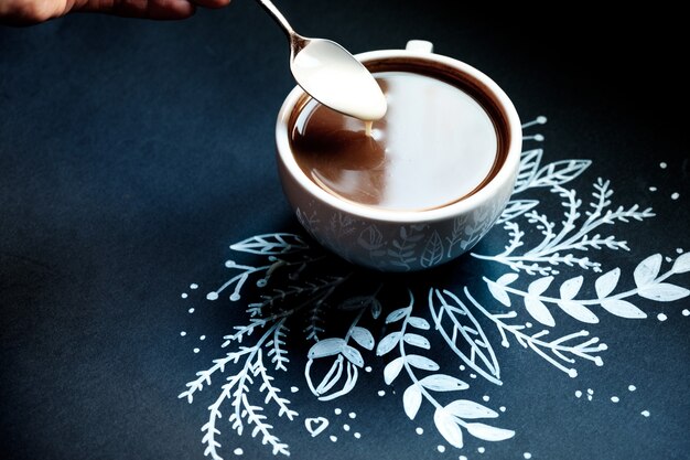 Pezzo di torta e una tazza di caffè su uno sfondo nero decorato con Capodanno. fiocco di neve dipinto di bianco.