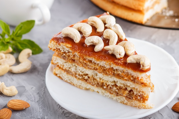 Pezzo di torta fatta in casa con crema al caramello e noci con una tazza di caffè sul cemento grigio