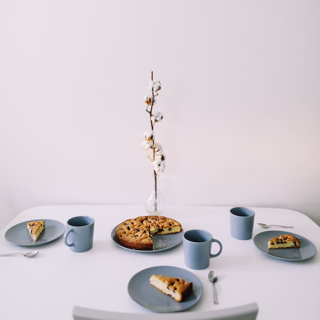 pezzo di torta sul piatto con una tazza di tè sul tavolo bianco colazione