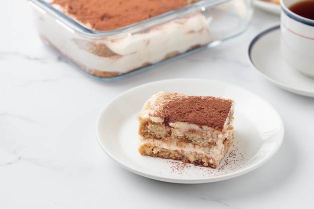 Pezzo di torta tiramisù fatta in casa dessert su uno sfondo di marmo bianco