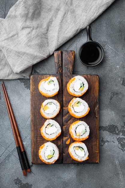 Philadelphia roll sushi con salmone, gamberi, avocado, set di formaggio cremoso, su sfondo di pietra grigia, vista dall'alto piatta