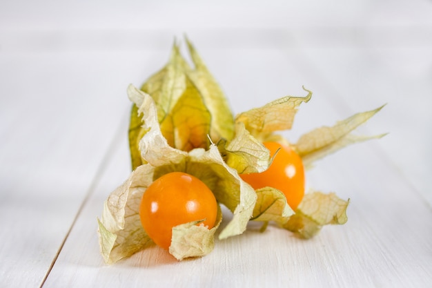 Physalis esotici delle bacche su una tavola di legno bianca.