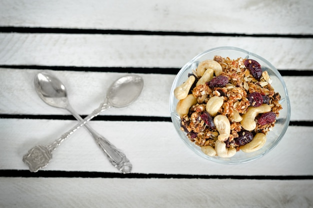 Piala con muesli e due cucchiai incrociati su una scatola di legno bianca. Avvicinamento