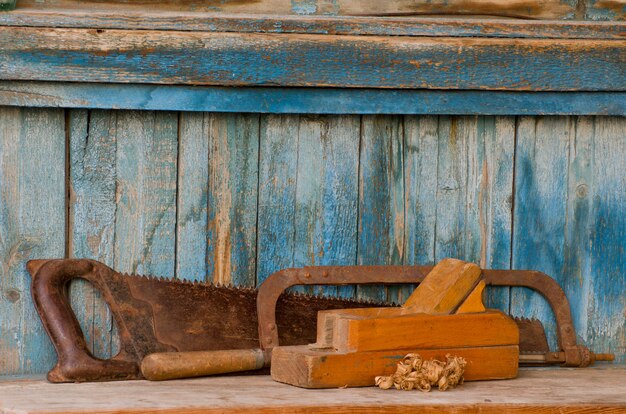 Pialla, seghetto e una sega su un vecchio tavolo di legno, patatine
