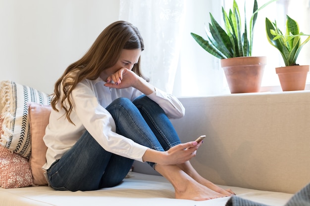 Piangere la giovane donna depressa guardando il telefono riceve cattive notizie