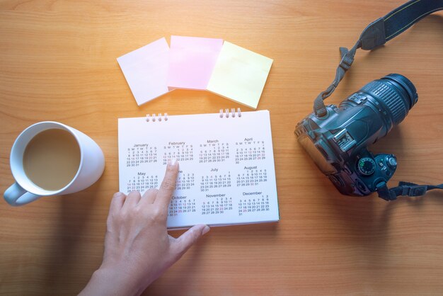 Pianifica il tuo viaggio sul calendario e usa il post-it per nota con una tazza di caffè su un tavolo di legno