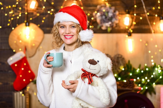 Pianifica qualche interessante attività natalizia. Ragazza con tazza di bevanda calda rilassante. Cose da fare prima di Natale. La donna con l'orsacchiotto beve il fondo delle decorazioni di natale del tè. Rilassati e ricaricati.