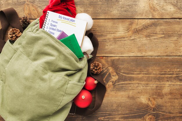 Pianificazione per il concetto di viaggio. Zaino con cappello di Babbo Natale, passaporti e blocco note con l'elenco dei paesi per il viaggio e decorazioni natalizie sulla vista del piano del tavolo in legno