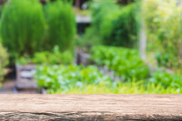 Piano d'appoggio in legno vuoto e albero verde sfocato e verdura nelle fattorie agricole. sfondo.