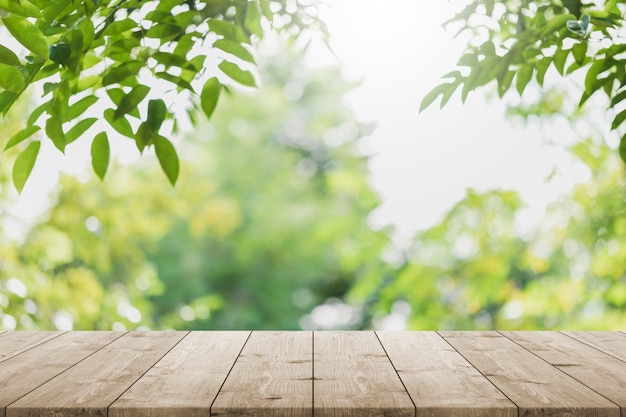 Piano d'appoggio in legno vuoto e albero verde sfocato nel giardino del parco