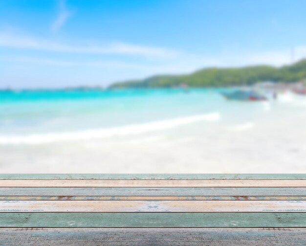 Piano del tavolo in legno con spiaggia tropicale sfocata con scena della natura e cielo blu, concetto di sfondo per le vacanze - può essere utilizzato per visualizzare o montare i tuoi prodotti