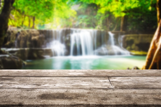 Piano del tavolo in legno sulla cascata sfocata nella foresta pluviale tropicale sullo sfondo di Huai Mae Khamin