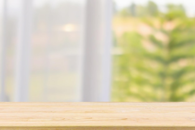 Piano del tavolo in legno vuoto con sfondo sfocato astratto della tenda della finestra per l'esposizione del prodotto