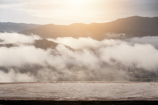 Piano del tavolo in pannello di legno con la montagna con sfondo paesaggio di nebbia.