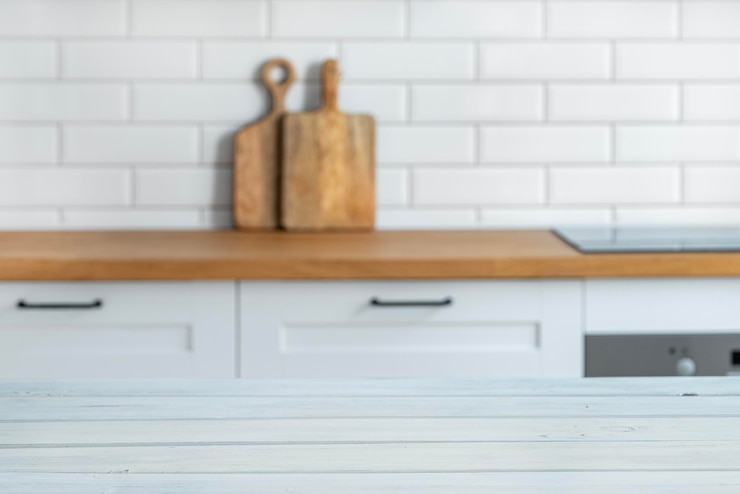 Foto piano di lavoro bianco in legno con spazio libero per il montaggio di un prodotto o layout sullo sfondo di una cucina bianca sfocata con tagliere