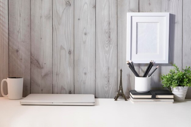 Pianta d'appartamento e cancelleria della tazza di caffè del computer portatile sul tavolo bianco