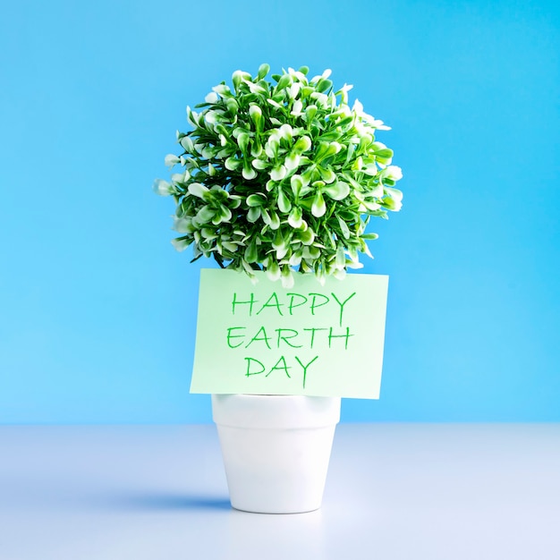 Pianta verde in vaso con Happy Earth Day.