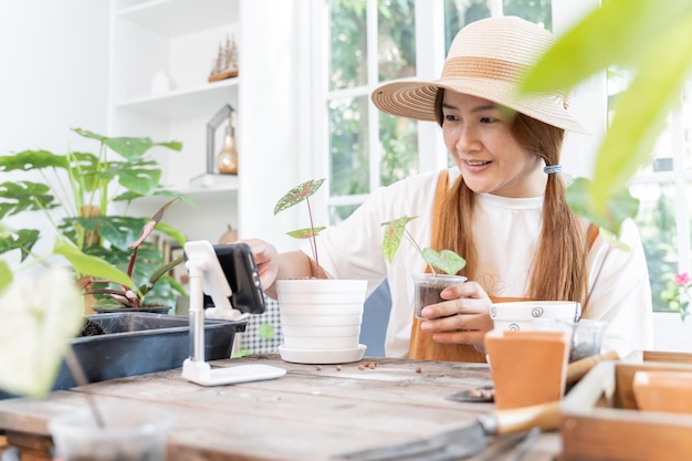 Piantare alberi al giardino botanico e utilizzare lo smartphone per la vendita online. Stile di vita della donna asiatica nella stagione primaverile.