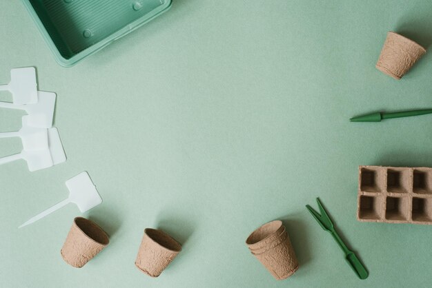 Piantare un fiore in un vaso di fiori Una composizione piatta con attrezzi da giardino e torba su sfondo verde Copia spazio