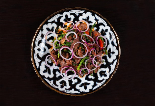 Piastra con carne tritata e verdure su sfondo nero Cucina asiatica