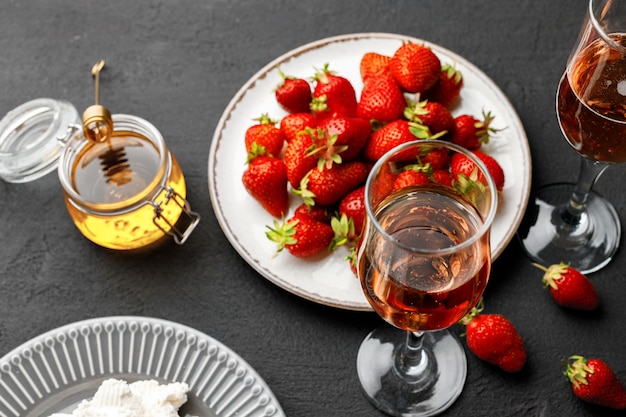 Piastra con fragole fresche e bicchiere di vino sulla fine nera su