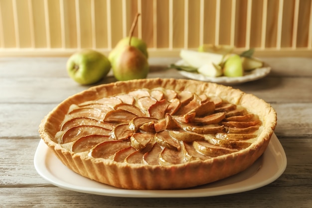 Piastra con gustosa torta di pere sulla tavola di legno