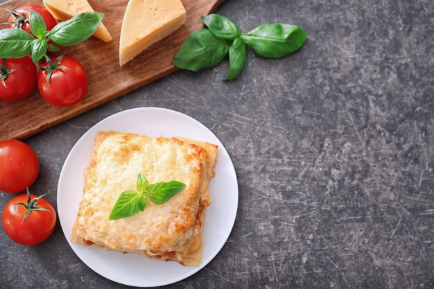 Piastra con gustose lasagne su sfondo grigio