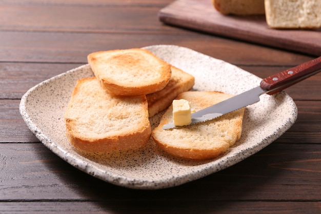 Piastra con gustosi pane tostato e burro sul tavolo