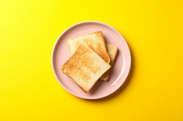 Piastra con gustosi toast su sfondo giallo, vista dall'alto