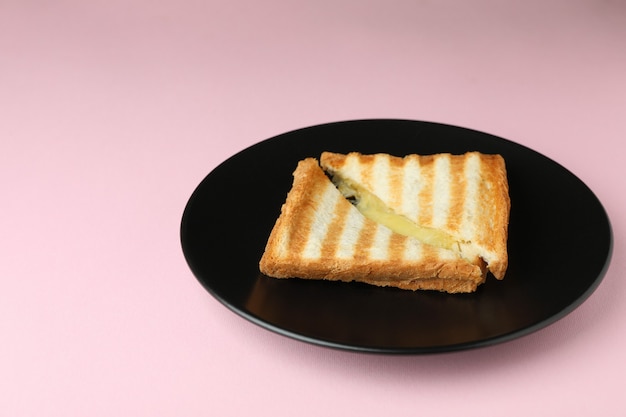 Piastra con gustoso panino alla griglia su sfondo rosa