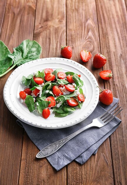 Piastra con insalata di spinaci alla fragola sulla tavola di legno