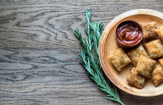 Piastra con ravioli fritti sulla tavola di legno