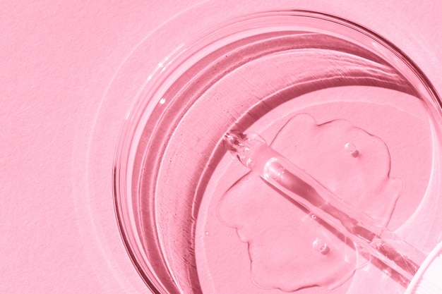 Piastra Petri Con gel trasparente La pipetta si trova Dispenser cosmetico Su uno sfondo rosa