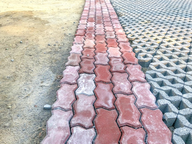 Piastrella per pavimento a blocchi di mattoni in pietra di colore grigio con erba verde e sabbia come sfondo o texture