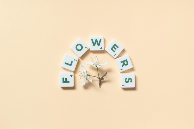 Piastrelle Scrabble con fiori primaverili su sfondo beige