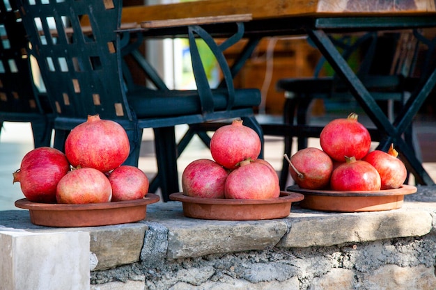 Piatti con un mucchio di frutti di melograno, preparati per il succo appena spremuto sul bancone di un caffè all'aperto.