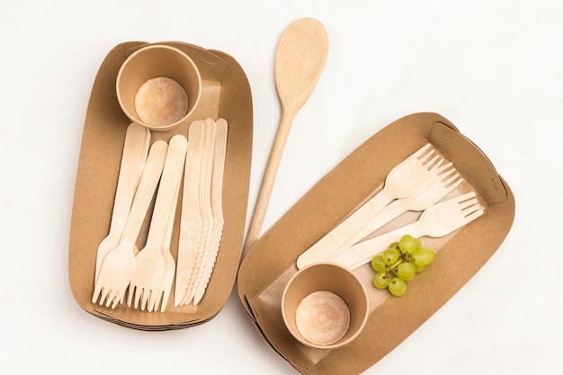 Piatti di cartone usa e getta, forchette e cucchiai di legno, piatti ecologici, sfondo bianco, piano piatto