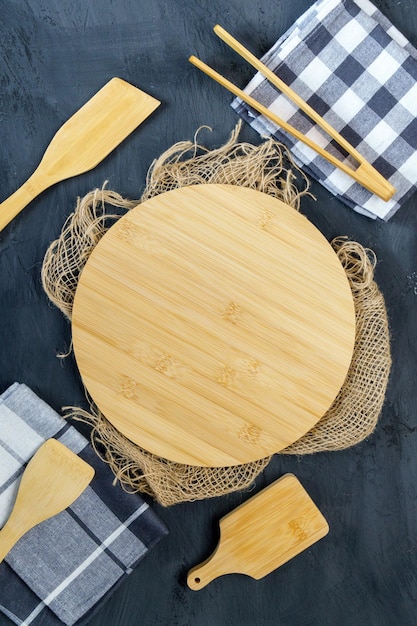 Piatti di legno vuoti utensili da cucina su sfondo nero Stoviglie ecofriendly Vista dall'alto Copia spazio Foto verticale