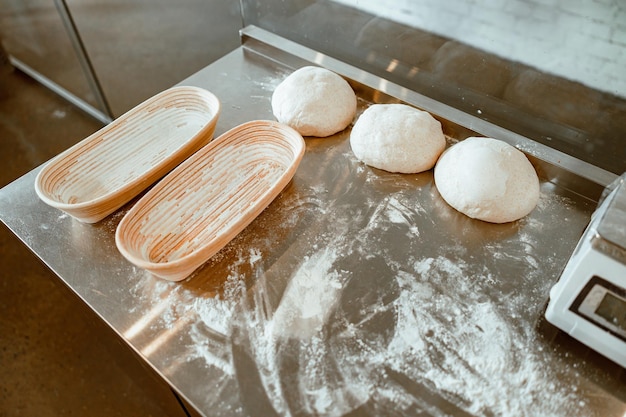 Piatti di pasta cruda e farina sparsa sul tavolo di metallo nel laboratorio di panetteria