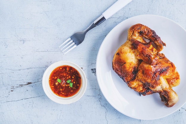 Piatti di pollo alla griglia e salsa di immersione su un pavimento di legno bianco