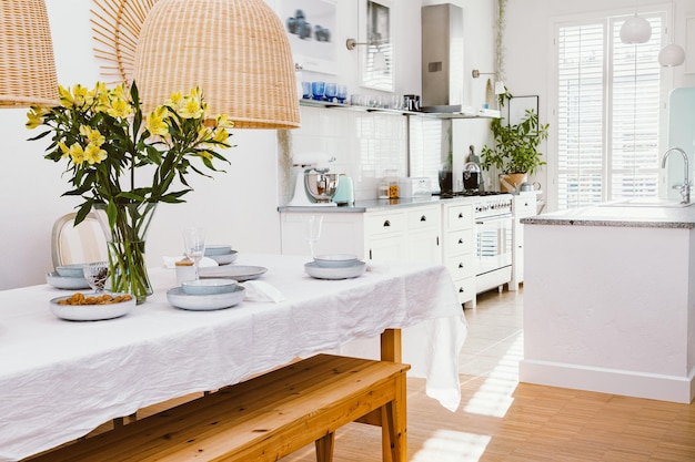 Piatti grigi bicchieri da vino e fiori gialli in vaso all'interno della sala da pranzo alla moda