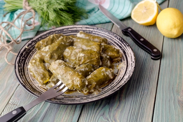 Piatti pronti Dolmas in salsa di egglemon in un piatto su un tavolo di legno primo piano Cucina greca